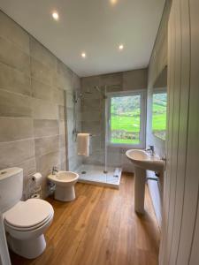 a bathroom with a toilet and two sinks and a shower at Lake Cottage - Panoramic views 7 Cidades in Sete Cidades