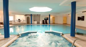 ein großer Pool mit blauen Säulen in einem Gebäude in der Unterkunft Elements Hotel Christlessee in Oberstdorf