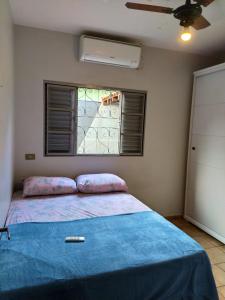 a bedroom with a bed with a blue blanket and a window at DOURADOS GUEST FLAT HOUSE in Dourados