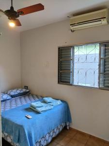 um quarto com uma cama com lençóis azuis e uma janela em DOURADOS GUEST FLAT HOUSE em Dourados