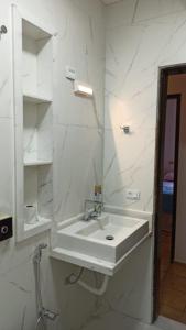 Baño blanco con lavabo y espejo en DOURADOS GUEST FLAT HOUSE, en Dourados