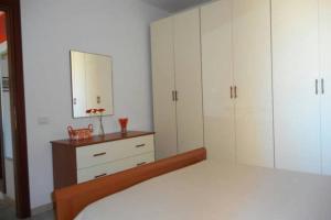 a bedroom with white cabinets and a bed with a mirror at Appartamento 72 in Torre Dei Corsari
