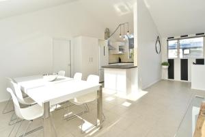 uma cozinha e sala de jantar com uma mesa branca e cadeiras em Moa Place - Christchurch Holiday Homes em Christchurch