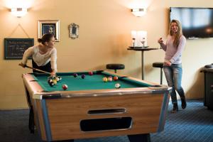 two women playing pool in a hotel room at Havila Hotel Geiranger in Geiranger