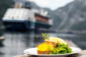 a plate of food with a salad and a lemon at Havila Hotel Geiranger in Geiranger