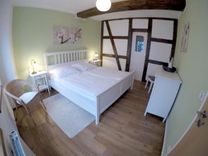 sypialnia z białym łóżkiem i drewnianą podłogą w obiekcie Zur alten Schäferei w mieście Zeulenroda-Triebes