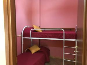 Cette chambre comprend 2 lits superposés et un mur rose. dans l'établissement Villafiorita, à Gioiosa Marea