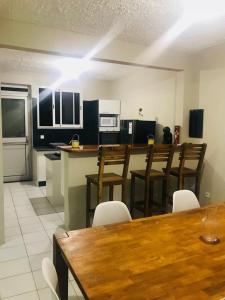 a kitchen with a wooden table and chairs and a kitchen with a counter at CHIRIJIEN BLÉ in Le Robert