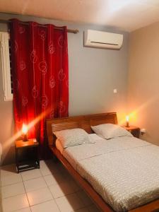 1 dormitorio con cama y cortina roja en CHIRIJIEN BLÉ, en Le Robert