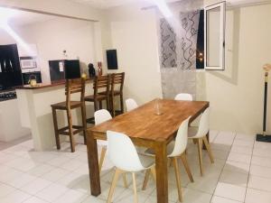 a dining room with a wooden table and white chairs at CHIRIJIEN BLÉ in Le Robert