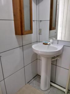 un bagno con un lavandino bianco e uno specchio di Recanto Figueira Silvestre a Cidreira Altre 42 foto