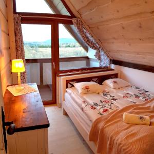 Schlafzimmer mit einem Bett, einem Tisch und einem Fenster in der Unterkunft Odludomki in Smerek