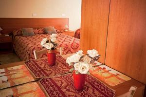 een slaapkamer met een bed en twee vazen met bloemen op een tafel bij Parioli House in Rome