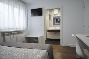 a bedroom with a bed and a sink and a mirror at Xabarin Rooms in Abadín