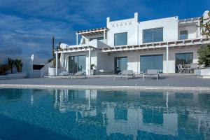 a white house with a swimming pool in front of it at Villa MED in Mikonos