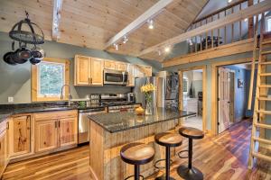a kitchen with wooden cabinets and a counter with stools at Newly Built Cabin with Hot Tub - 16 Mi to Stowe Mtn! in Morristown