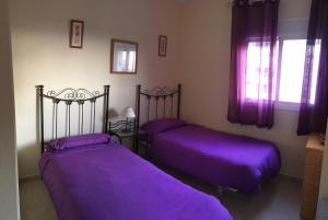 2 camas en una habitación con sábanas moradas en EL BALCÓN DE MAR, en Nerja