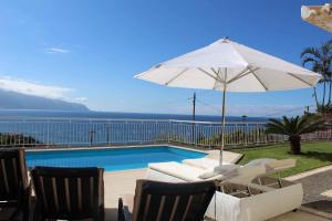 Villa Quinze - Luxurious 3 bedroom Villa with private pool and games room & amazing views في بونتا ديلغادا: مسبح فيه مظله بيضاء وكراسي ومسبح