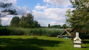 un campo de hierba con una casa frente a un lago en Ferienhaus Am Eichler Stich, en Zehdenick