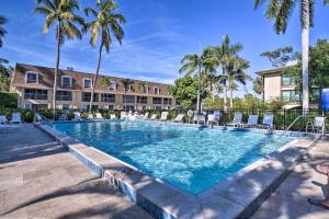 a large swimming pool with chairs and palm trees at Coastal Downtown Naples Condo - Walk to the Beach! in Naples