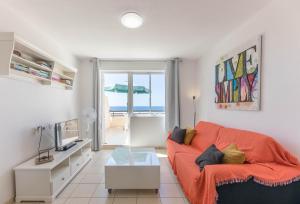 a living room with a orange couch and a view of the ocean at terrazza e vista oceano, Wi-Fi, aria condizionata, 6º piano in Morro del Jable