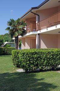 a house with a hedge in front of a building at Camping Garden Tourist in Manerba del Garda