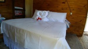 a white bed with a stuffed animal on it at Cabanas Fazenda da Raia in Urubici