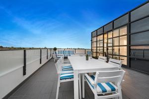 a balcony with a table and chairs on a roof at The Hamptons Apartments - St Kilda in Melbourne