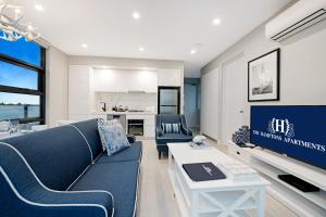 a living room with a blue couch and a tv at The Hamptons Apartments - St Kilda in Melbourne