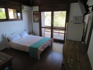 1 dormitorio con 1 cama y puerta al porche en Pousada Águas de Ibiraquera Suíte Luz en Imbituba