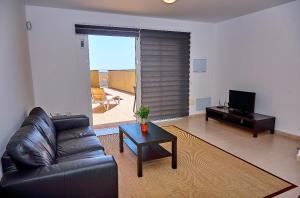 a living room with a black leather couch and a table at Medano Beach Villas in El Médano