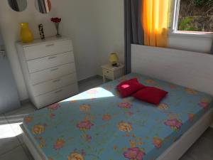 a bedroom with a bed with a floral bedspread and red pillows at Location Vacances in Deshaies