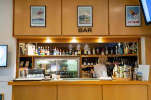 Une femme derrière le comptoir d'un bar dans l'établissement Heartland Hotel Queenstown, à Queenstown