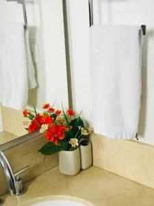 a vase of flowers sitting on a sink in a bathroom at MORROS CITY ESPECTACULAR FRENTE A LA PLAYA in Cartagena de Indias