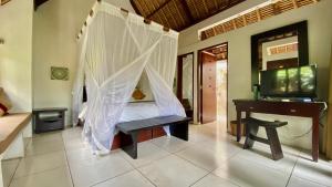 a bedroom with a bed with a desk and a net at Villa Pantulan Bali in Ubud