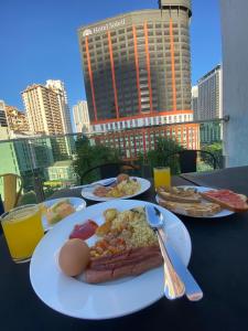 einen Tisch mit Teller mit Lebensmitteln und Blick auf die Stadt in der Unterkunft Melange Boutique Hotel Bukit Bintang in Kuala Lumpur