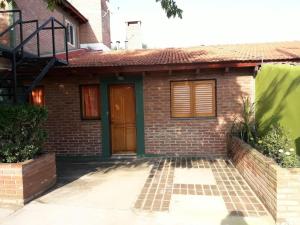 mały ceglany dom z brązowymi drzwiami w obiekcie Ariel Reynoso - Departamento Planta Baja w mieście Mina Clavero