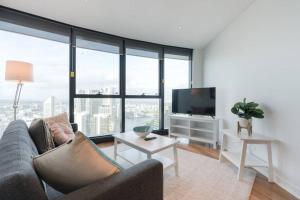 sala de estar con sofá y TV de pantalla plana en Lvl 57 Skytower Breathtaking Views CBD Wifi Carpark by Stylish Stays en Brisbane