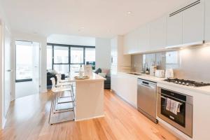 a kitchen with white cabinets and a stove top oven at Lvl 57 Skytower Breathtaking Views CBD Wifi Carpark by Stylish Stays in Brisbane