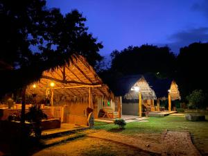una casa con tetto di paglia di notte di Hasthi Safari Cottage a Udawalawe