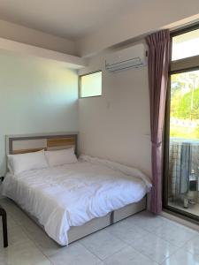 1 dormitorio con 1 cama, ventana y ventana en Jin Ji Homestay, en Minxiong