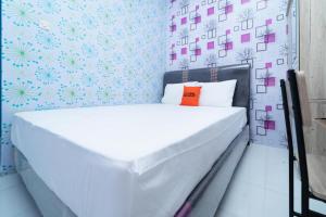 een wit bed in een kamer met blauw en roze behang bij KoolKost At Menceng Raya - Minimum Stay 30 Nights in Jakarta