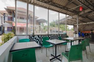 een restaurant met groene stoelen en tafels en ramen bij RedDoorz near RS Harapan Pematang Siantar in Pematangsiantar