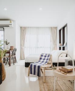 um quarto branco com uma cama, uma cadeira e uma mesa em Siamplaengna Residence สยามแปลงนา เรสซิเดนท์ em Banguecoque