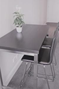 a black table with two chairs and a potted plant at Executive stay Little Collins street in Melbourne