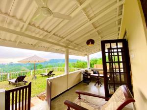 a screened in porch with chairs and an umbrella at The Horizon Hill Top Villa in Unawatuna