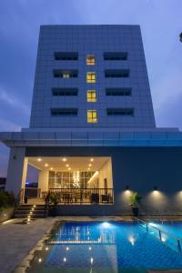 a building with a swimming pool in front of a building at Hotel Santika Pasir Koja Bandung in Bandung