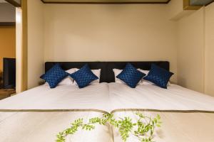 a large bed with blue pillows on it at Fuji Heights in Osaka