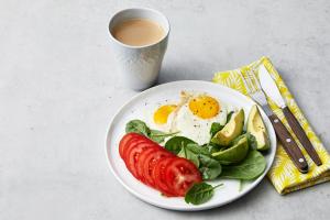 a plate of food with an egg and a salad and a cup of coffee at Hotel Venisi in Prizren