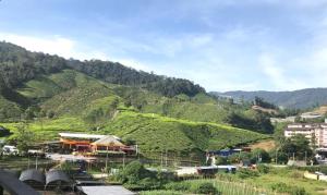Cameron Highlands Modern7-Tea Plantation View-Premium Hotel Bed في Kampung Kuala Terla: اطلاله على جبل مع مدينه وبيوت